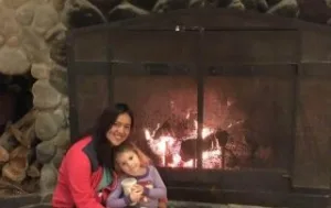 Au Pair and Host Kid in front of a fireplace