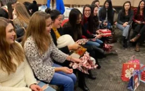 Au Pairs laughing while exchanging white elephant gifts.