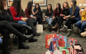 Au Pairs sit down to exchange white elephant gifts.