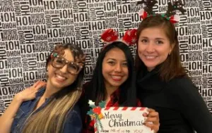 Au Pairs posing with "Merry Christmas" sign in the photo booth.