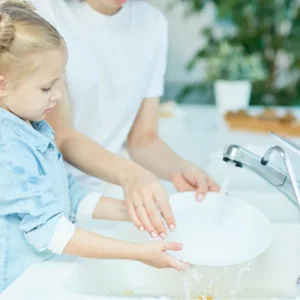 Au Pair and child washing dishes