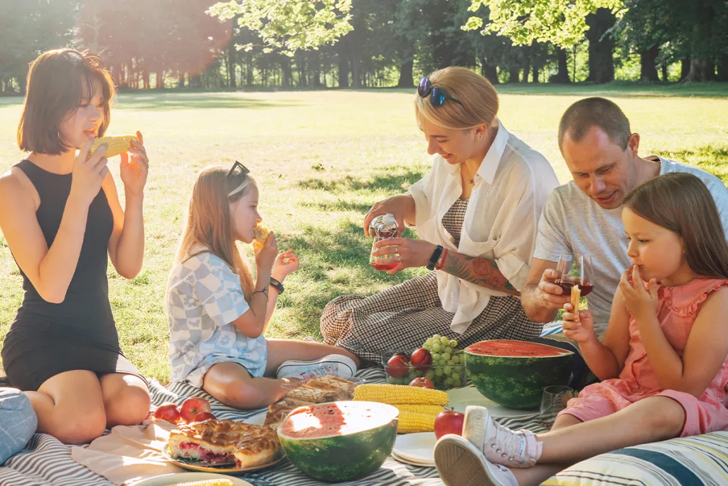 A mom, dad, and two daughters share one of their top family bonding activities with their au pair—a picnic in a sunny park.