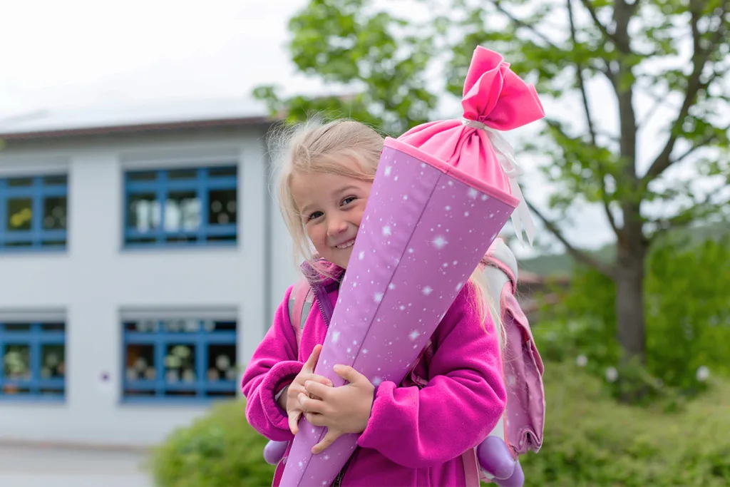 A young girl holds her Schultüte on the first day of school to celebrate one of her favorite German traditions and customs.