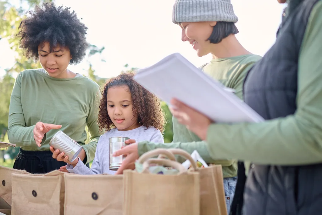 Caretakers are teaching empathy to kids while volunteering with a young girl at a soup drive to give back to their community.