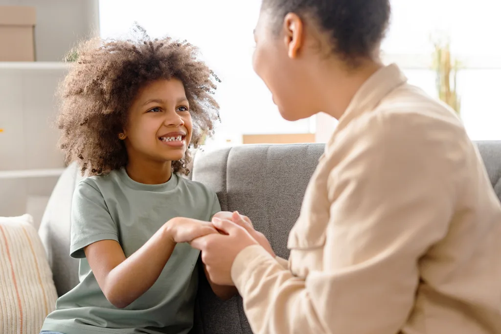 An au pair dedicated to building resilience in children sits and holds hands with a child to show them love and support.