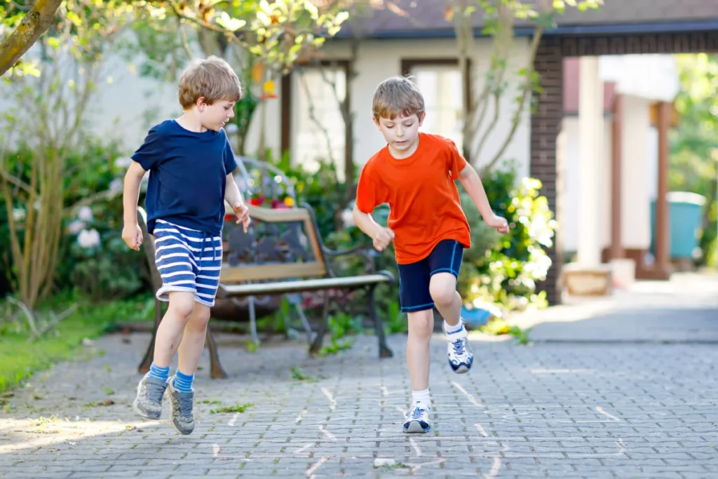 Two young boys in casual clothing play what might be a traditional French game similar to hopscotch, called La Marelle.